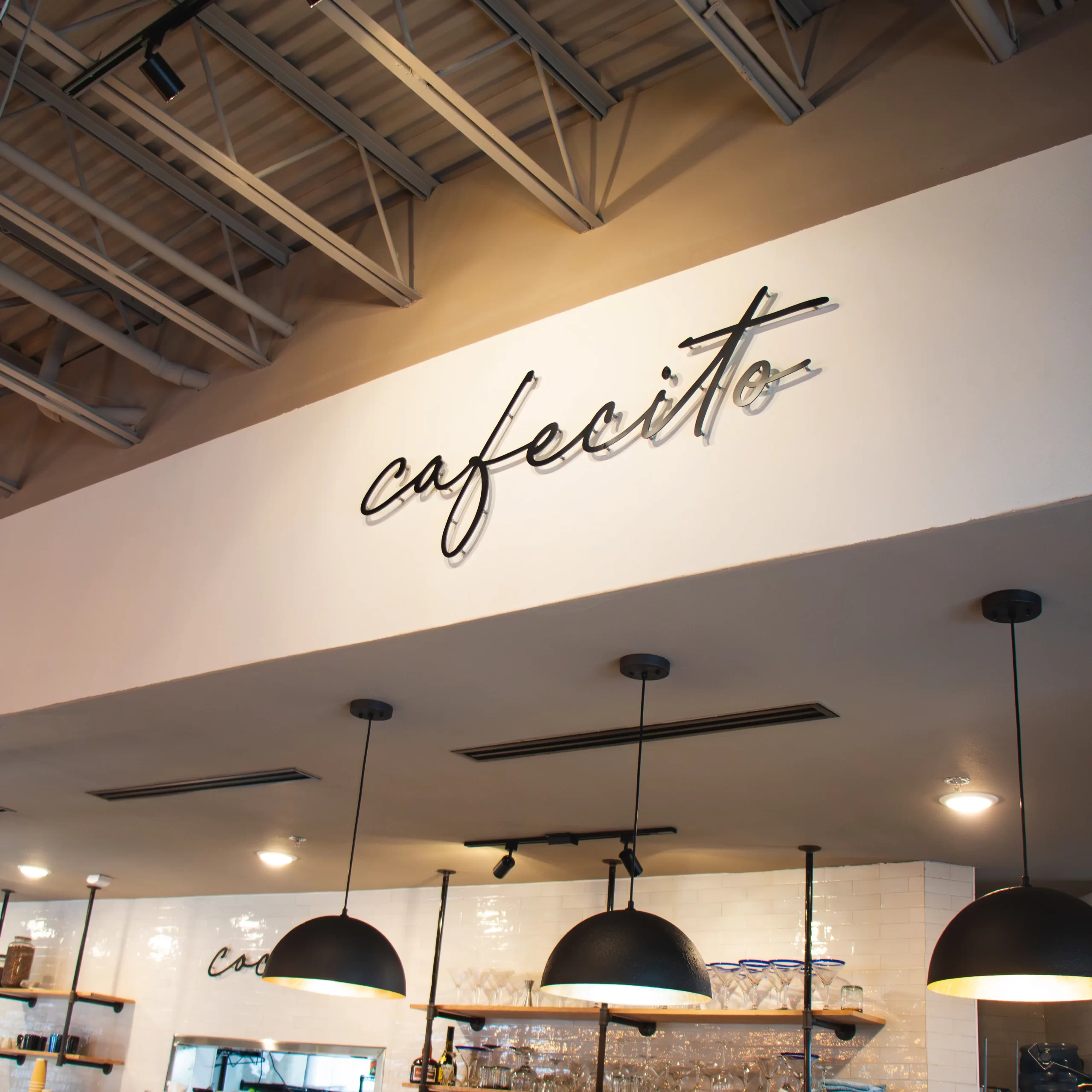 Black aluminum signage with cursive lettering for Panadería Cafecito Cocina